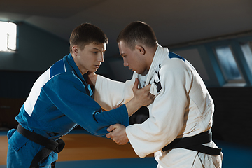 Image showing Two young judo fighters in kimono training martial arts in the gym with expression, in action and motion