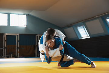 Image showing Two young judo fighters in kimono training martial arts in the gym with expression, in action and motion