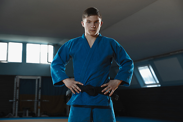 Image showing Young judo fighter in kimono posing comfident in the gym, strong and healthy