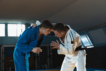 Image showing Two young judo fighters in kimono training martial arts in the gym with expression, in action and motion