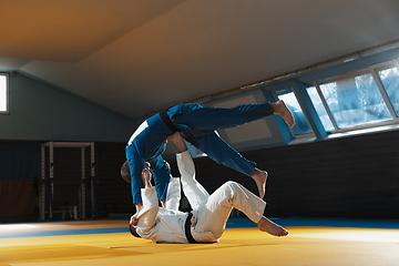 Image showing Two young judo fighters in kimono training martial arts in the gym with expression, in action and motion