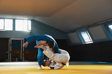 Image showing Two young judo fighters in kimono training martial arts in the gym with expression, in action and motion