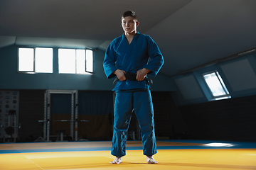 Image showing Young judo fighter in kimono posing comfident in the gym, strong and healthy