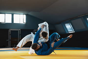 Image showing Two young judo fighters in kimono training martial arts in the gym with expression, in action and motion