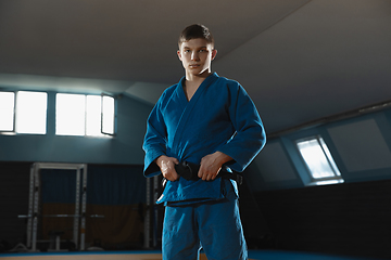 Image showing Young judo fighter in kimono posing comfident in the gym, strong and healthy