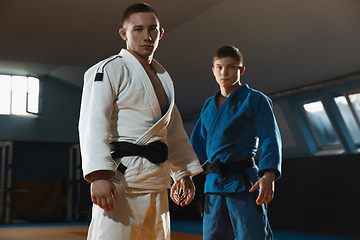 Image showing Two young judo fighters in kimono posing comfident in the gym, strong and healthy