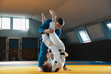 Image showing Two young judo fighters in kimono training martial arts in the gym with expression, in action and motion