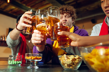 Image showing Sport fans cheering at bar, pub and drinking beer while championship, competition is going