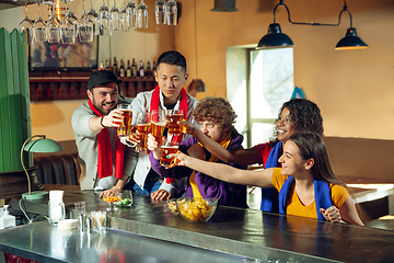 Image showing Sport fans cheering at bar, pub and drinking beer while championship, competition is going