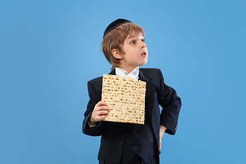 Image showing Portrait of a young orthodox jewish boy isolated on blue studio background, meeting the Passover