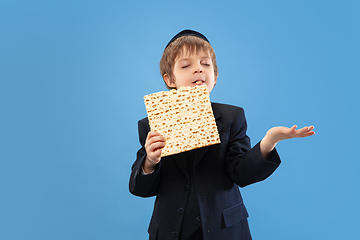 Image showing Portrait of a young orthodox jewish boy isolated on blue studio background, meeting the Passover