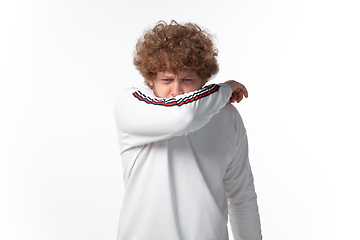 Image showing How coronavirus changed our lives. Young man sneezing on white background