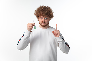 Image showing How coronavirus changed our lives. Young man checking, taking temperature on white background