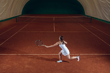 Image showing Young caucasian professional sportswoman playing tennis on sport court background