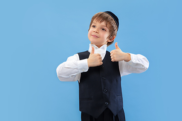 Image showing Portrait of a young orthodox jewish boy isolated on blue studio background, meeting the Passover