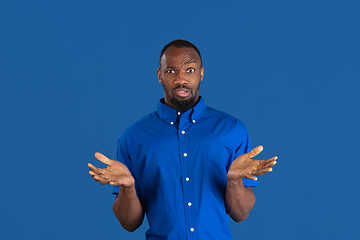 Image showing Monochrome portrait of young african-american man on blue studio background