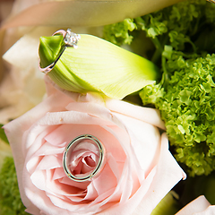 Image showing wedding rings lie on a beautiful bouquet as bridal accessories