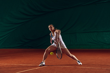 Image showing Young caucasian professional sportswoman playing tennis on sport court background