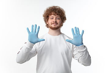 Image showing How coronavirus changed our lives. Young man holding thermometer, taking temperature on white background