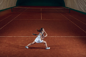 Image showing Young caucasian professional sportswoman playing tennis on sport court background