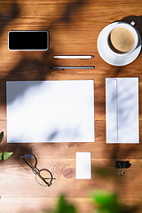 Image showing Creative and cozy workplace at home office, inspirational mock up with plant shadows on table surface