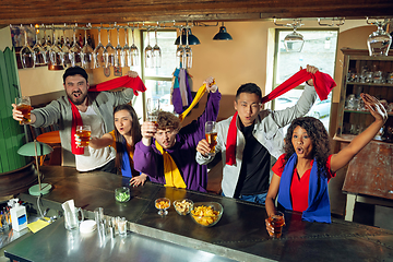 Image showing Sport fans cheering at bar, pub and drinking beer while championship, competition is going