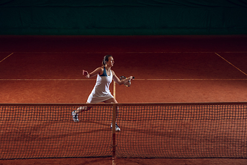 Image showing Young caucasian professional sportswoman playing tennis on sport court background