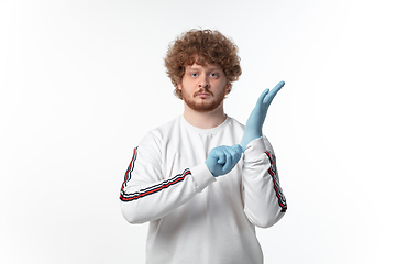 Image showing How coronavirus changed our lives. Young man holding thermometer, taking temperature on white background