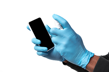 Image showing How coronavirus changed our lives. Young man disinfecting gadgets surfaces on white background