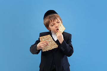 Image showing Portrait of a young orthodox jewish boy isolated on blue studio background, meeting the Passover