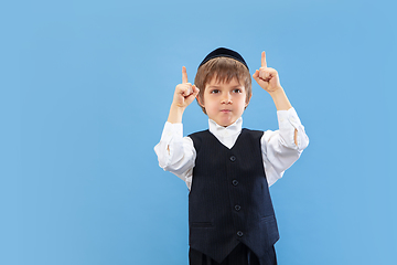 Image showing Portrait of a young orthodox jewish boy isolated on blue studio background, meeting the Passover