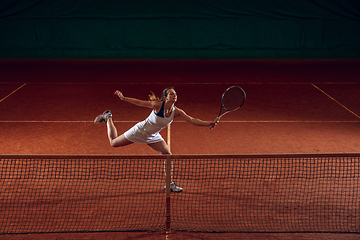 Image showing Young caucasian professional sportswoman playing tennis on sport court background