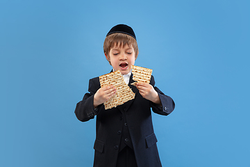 Image showing Portrait of a young orthodox jewish boy isolated on blue studio background, meeting the Passover