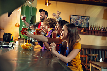 Image showing Sport fans cheering at bar, pub and drinking beer while championship, competition is going