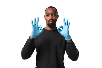 Image showing How coronavirus changed our lives. Young man holding thermometer, taking temperature on white background