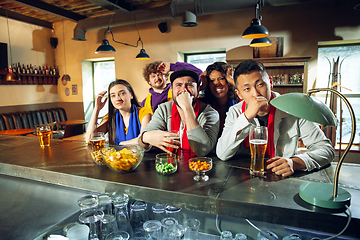 Image showing Sport fans cheering at bar, pub and drinking beer while championship, competition is going