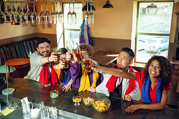 Image showing Sport fans cheering at bar, pub and drinking beer while championship, competition is going