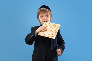 Image showing Portrait of a young orthodox jewish boy isolated on blue studio background, meeting the Passover