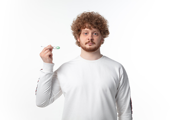 Image showing How coronavirus changed our lives. Young man checking, taking temperature on white background