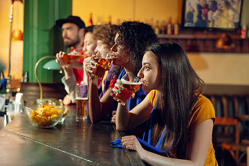 Image showing Sport fans cheering at bar, pub and drinking beer while championship, competition is going