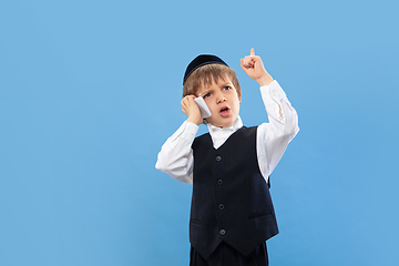 Image showing Portrait of a young orthodox jewish boy isolated on blue studio background, meeting the Passover