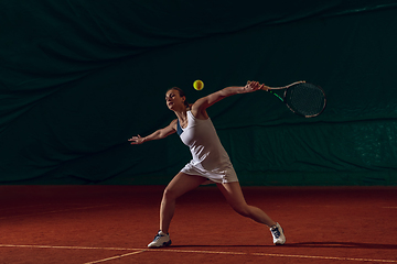 Image showing Young caucasian professional sportswoman playing tennis on sport court background