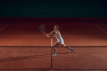 Image showing Young caucasian professional sportswoman playing tennis on sport court background