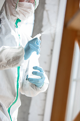 Image showing Coronavirus Pandemic. A disinfector in a protective suit and mask sprays disinfectants in the house or office