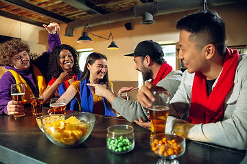 Image showing Sport fans cheering at bar, pub and drinking beer while championship, competition is going