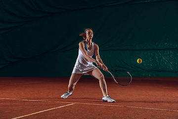 Image showing Young caucasian professional sportswoman playing tennis on sport court background