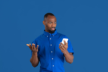 Image showing Monochrome portrait of young african-american man on blue studio background