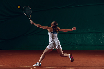 Image showing Young caucasian professional sportswoman playing tennis on sport court background