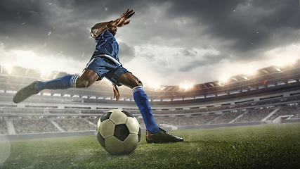 Image showing Football or soccer player in action on stadium with flashlights, kicking ball for winning goal, wide angle