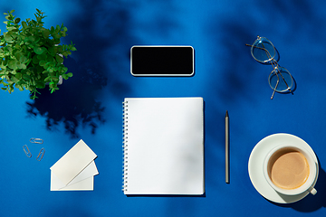 Image showing Creative and cozy workplace at home office, inspirational mock up with plant shadows on table surface